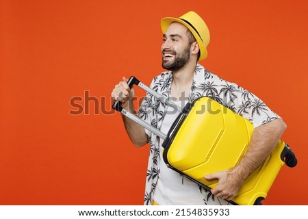 Traveler tourist fun man wear summer casual clothes hat hold suitcase bag look aside isolated on plain orange background studio. Passenger travel abroad on weekends getaway. Air flight journey concept Stock foto © 