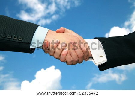business team work. Handshake to seal the agreement on sky background