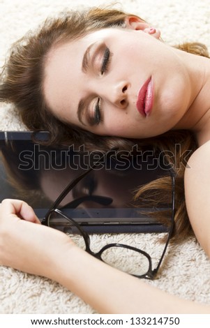 Girl sleeping on the carpet with a tablet PC.