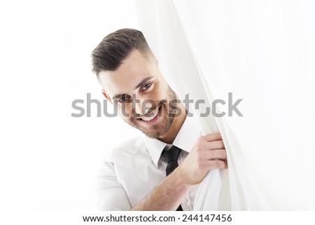 smiling businessman looking at the camera from behind a white curtain