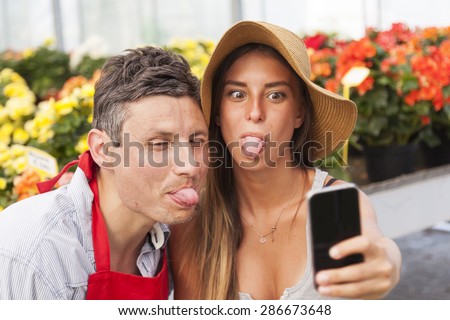 couple of flower sellers take a funny selfie in greenhouse