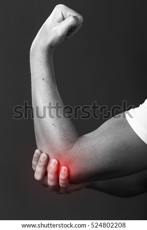 Elbow pain. Man holding his elbow. Pain concept close-up  on gray background  black and white with red accent Stock fotó © 