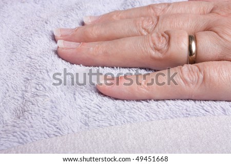 Older senior woman's hand receiving home spa/beauty treatment of nail extensions.