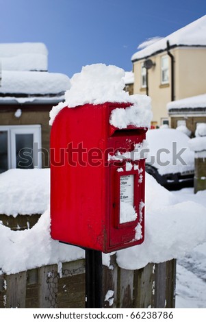 Picturesque winter scenic of thick covering of snow and red post box.