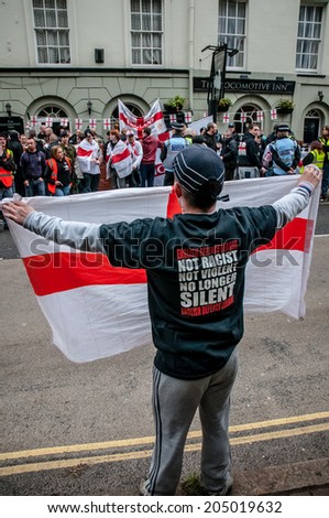 EXETER, UK - NOVEMBER 16: English Defence League member holds up a St George flag to EDL supporters during the English Defence League march and rally November 16, 2013 in Exeter, Devon, UK