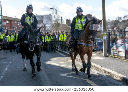 EXETER, ENGLAND - FEBRUARY 21, 2015: Police horses escort Plymouth Argyle football fans during the police operation at the League 2 football match between Exeter City FC and Plymouth Argyle FC