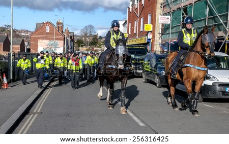 EXETER, ENGLAND - FEBRUARY 21, 2015: Devon and Cornwall Police escort football fans away during the police operation at the League 2 football match between Exeter City FC and Plymouth Argyle FC