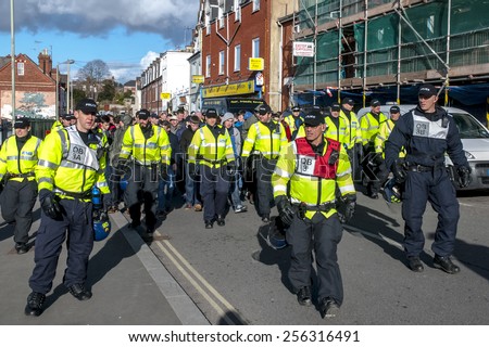 EXETER, ENGLAND - FEBRUARY 21, 2015: Devon and Cornwall Police escort Plymouth football fans during the police operation at the League 2 football match between Exeter City FC and Plymouth Argyle FC