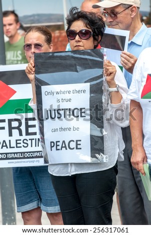 EXETER, ENGLAND - JULY 15, 2014: Peace campaigner hold a sign, which demands Justice and peace during the Peace Vigil for Gaza in Exeter's Princesshay Square.