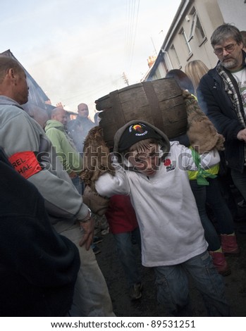 OTTERY ST MARY -  NOVEMBER 5: A young unidentified barrel roller runs through the crowd with a burning barrel at the 2011 Tar Barrels of Ottery Carnival  on  November 5, 2011 in Ottery St Mary