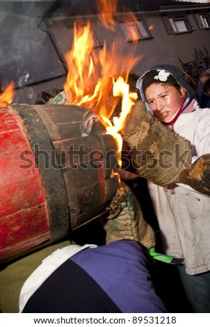 OTTERY ST MARY -  NOVEMBER 5: An unidentified barrel roller is left with burning gloves as she exchanges the barrel with another roller at 2011 Tar Barrels of Ottery Carnival on  November 5, 2011 in Ottery St Mary