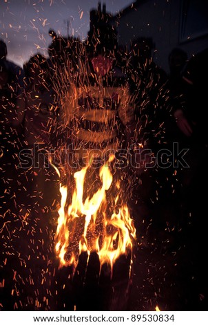 OTTERY ST MARY -  NOVEMBER 5: A young barrel roller stands over a burning barrel in a shower of sparks at the 2011 Tar Barrels of Ottery Carnival on  November 5, 2011 in Ottery St Mary