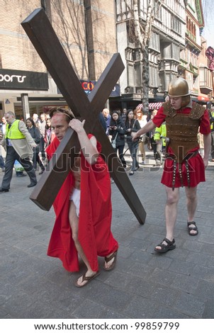 EXETER - APRIL 6: Actor who plays Jesus carries the cross through the streets of Exeter during the Good Friday Walk of Witness in Exeter City Centre on April 6, 2012 in Exeter, UK