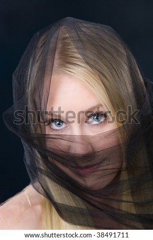 young blonde woman with blue eyes wearing sheer black veil head and covering half of her face