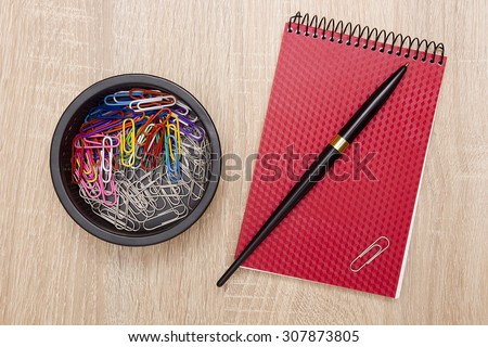 Office notebook and office paper clips on the desk.