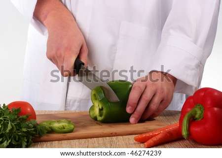 The cook cuts the big kitchen knife green pepper on a kitchen board.