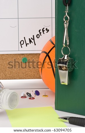 A silver whistle on a green notebook next to a basketball and a calendar with the date of the playoffs on it.