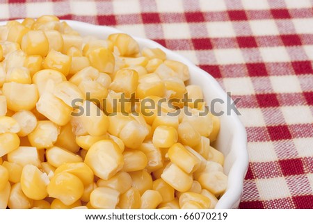 Canned corn in a white bowl on a checkered tablecloth
