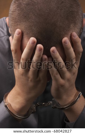 Arrested in handcuffs covered his face with his hands.