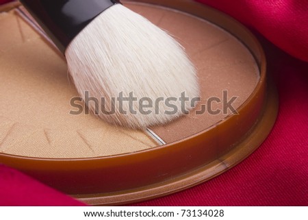 Powder brush and brown powder on a red background.