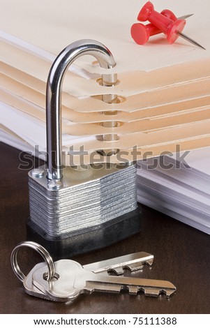 Stack of manila folders closed with a metal lock.