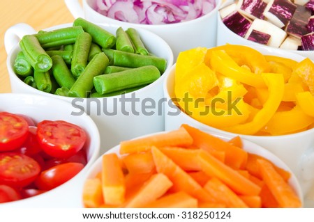 Cut vegetables of rainbow colors in white bowls