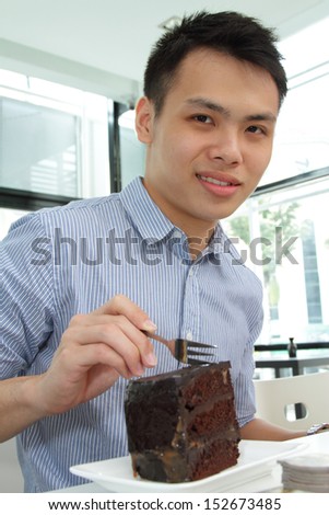 An Asian man having a chocolate cake