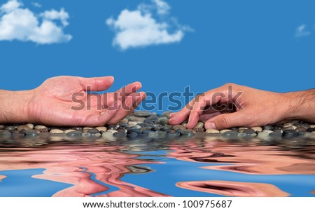 Two hands laying on pebbles near water