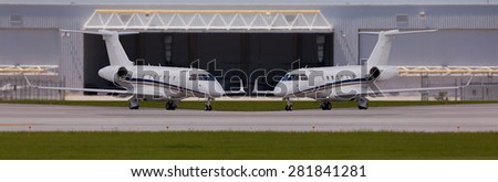 Two private planes in front of a hangar