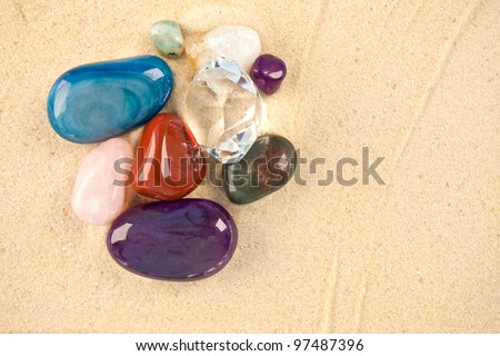 A collection of beautiful precious stones laying on sand