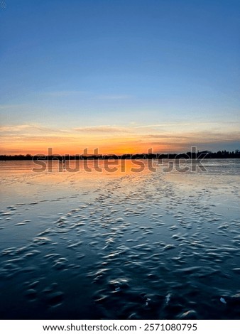 Similar – Image, Stock Photo Sunset over a frozen lake. Sunbeams falling on water. Shadows of trees on the ice covering the lake. Aerial view of a frozen lake. Ice sheet background. Frozen grass in water