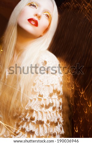 Beautiful model with luxury makeup, sexy lips and fashion sweater. Real lights effect: mixed light with long exposure.