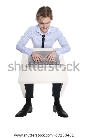 Young businessman, office worker or student with laptop, Stuido photo of young man sitting at funny small table.