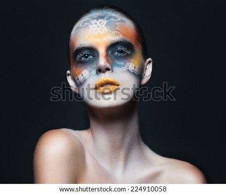Portrait of beautiful glamor girl with dark eye make-up in the form of lace and orange lips on black