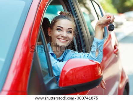Young cheerful woman sitting in a car with keys in hand - concept Rent a car
