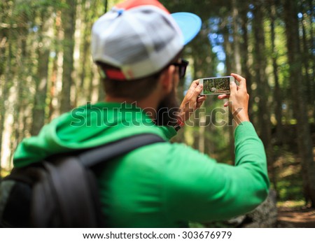 Man makes photos on a smartphone in the coniferous forest in the national park Durmitor, Montenegro, Balkans