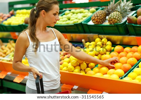 Young beautiful woman shopping in a supermarket in the department of fruit and vegetables