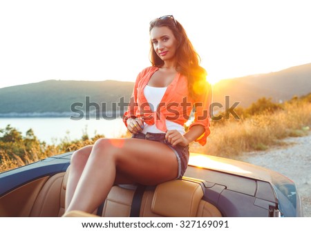 Beautiful woman sitting in cabriolet, enjoying trip on luxury modern car with open roof, fashionable lifestyle concept