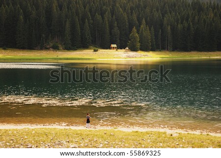child on shore of mountain lake throwing rocks