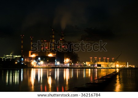 A Steam powered power plant near the sea shoot at night, a common icon for global warming.