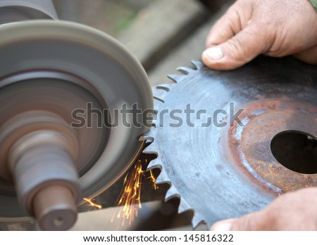 a worker sharpens a circular saw blade