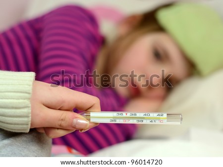 Mother check daughters fever on thermometer