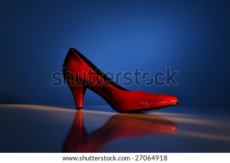 High heel red shoe on blue background, close up