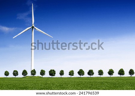 Wind Turbine on front of a green wheat field and line of trees