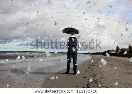 Image of a business person standing under money rain with umbrella