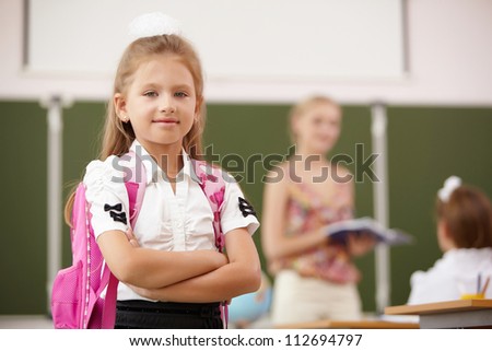 Little blonde girl studying at school class