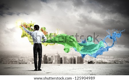 young man standing with back painting splashes against city background