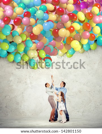 Image of happy family holding bunch of colorful balloons