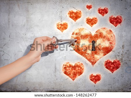 Close up of human hand with key opening heart