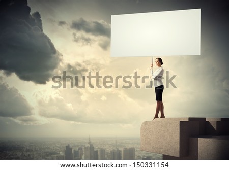 Image of business woman standing atop of building holding blank banner